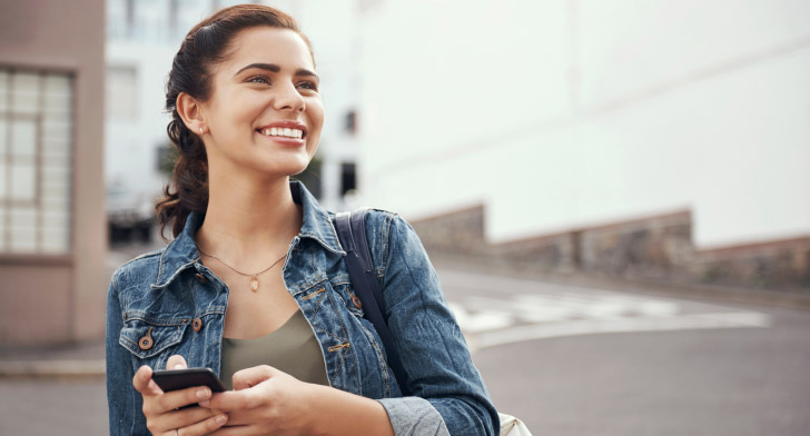 Personne à l’extérieur utilisant un smartphone pour consulter des offres immobilières